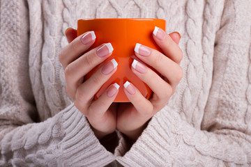 Woman holds an orange cup close up.
