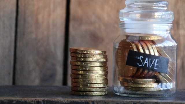 Save idea, gold coins in a glass jar,  inscription save and a stack of gold coins