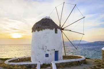 A windmill in Chora,Mykonos,Greece at sunset.Traditional greek whitewashed architecture,popular landmark,tourist attraction against the blue sky and the Aegean sea. The wind mills are now decorative. © f8grapher