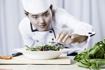 close up of female chef patiently placing salad on a plate