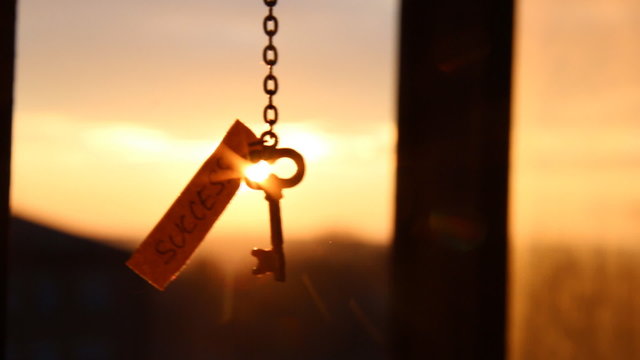 Key and text "success" against sunset rays Light.  Golden key to success concept.