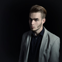 Portrait of attractive mysterious young man over black backgroun