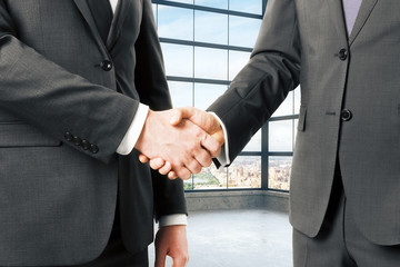 Business partners shake hands in empty loft office