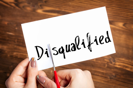 Woman hands cutting card with the word disqualified