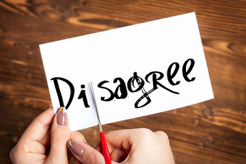 
Woman hands cutting card with the word disagree