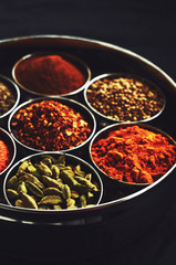 Set of traditional indian spices in metal bowls on black backgro