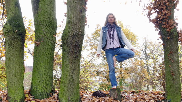 yoga exercise on a tree stump in autumn
