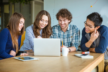 Group of positive cheerful students doing homework together in classroom