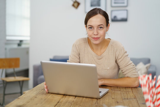 moderne junge frau sitzt in ihrer wohnung und arbeitet am laptop
