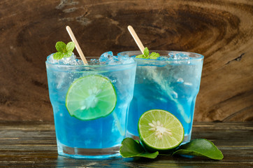 Ice blue drink with lemon on wooden background