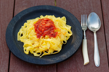 Tagliatelle with tomato sauce in wooden plate