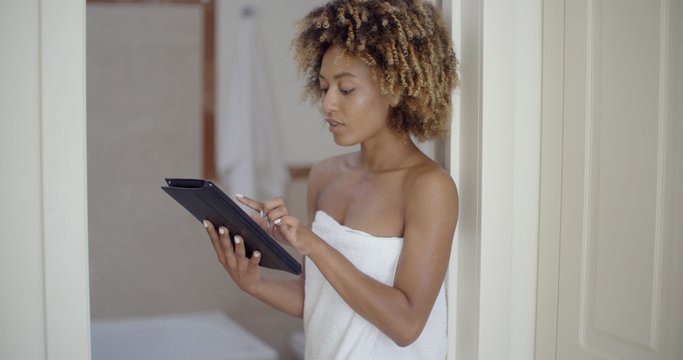 Woman Using Tablet Computer In Bathroom