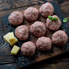Close-up of uncooked meatballs on a rustic wooden chopping board