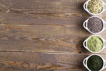 Superfood raw seeds and powder. Body building powders and health food on wooden background. Superfood served in small bowls.