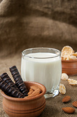 A glass of milk with almond nuts, corn flakes, chocolates,  on sacking burlap back ground 