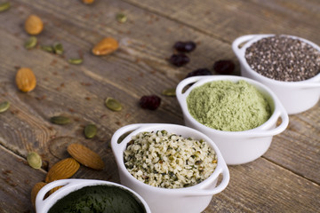 Superfood raw seeds and powder. Body building powders and health food on wooden background. Superfood served in small bowls.