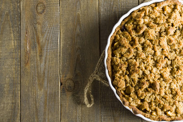 Pie with crumble on plank background. Apple crumble. Apple pie with crumble on wooden background. 