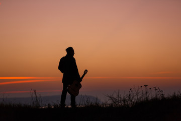 Man with guitar in sunset