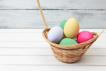 Easter eggs in basket on white wooden background