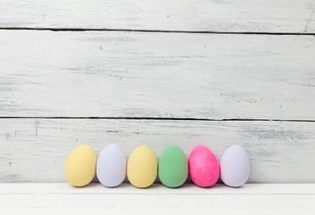 Easter eggs painted in pastel colors on white wooden background