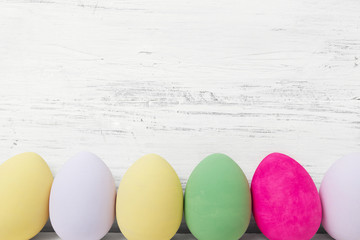Easter eggs painted in pastel colors on white wooden background