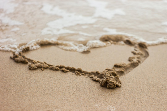 heart drawn in the sand on the beach