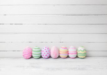 Easter eggs painted in pastel colors on white wooden background.