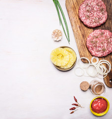 Fototapeta na wymiar ingredients for a burger, onion leaves, tomato sauce, onion rings, pineapple border ,place for text on wooden rustic background top view