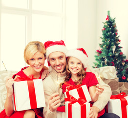 Obraz na płótnie Canvas happy family in santa helper hats with gift boxes