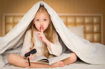 little girl sitting on the bed and reading a book