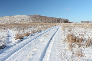 Obraz premium Snow automobile road going near a hill Bald, Bugotaksky hills, the Novosibirsk region, Russia