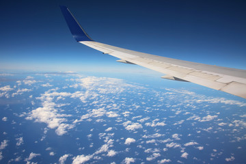 Obraz premium Wing of airplane above white clouds
