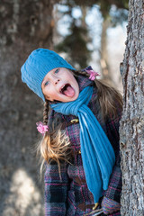 Girl behind the tree showing her funny face with tongue