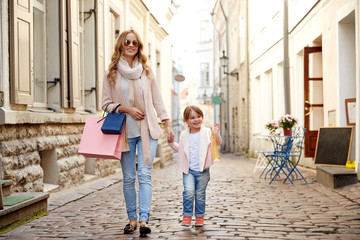 happy mother and child with shopping bags in city