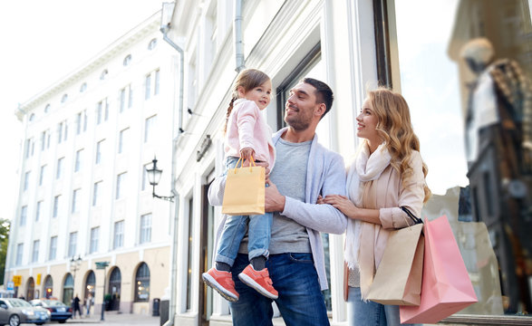 Happy Family With Child And Shopping Bags In City