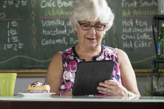 Senior Woman Using An Ipad/tablet In A Coffee Shop