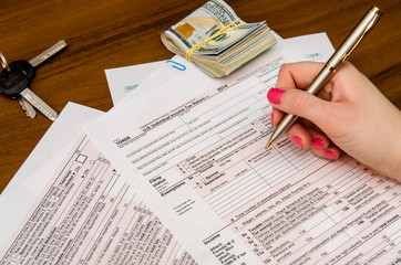 Obraz premium Woman hand filling income tax forms 1040