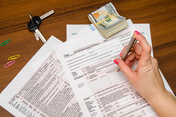 Obraz premium Woman hand filling income tax forms 1040