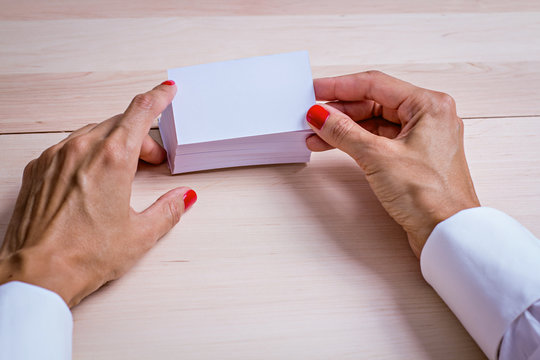 Кисти рук держащие белую визитную карточку