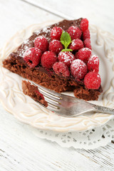 Piece of cake with chocolate Glaze and raspberries on color wooden background