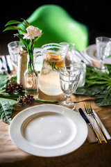 A carafe of fruity beverage with mint and lemon on a decorated table ready for dinner. Beautifully decorated table set for wedding or another event in the restaurant.