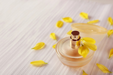 Bottle of perfume and rose petals on fabric background