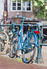 Parked blue bicycle on a railing in the historic canal belt, Amsterdam, The Netherlands