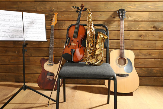 Musical instruments on a chair and note holder against wooden background