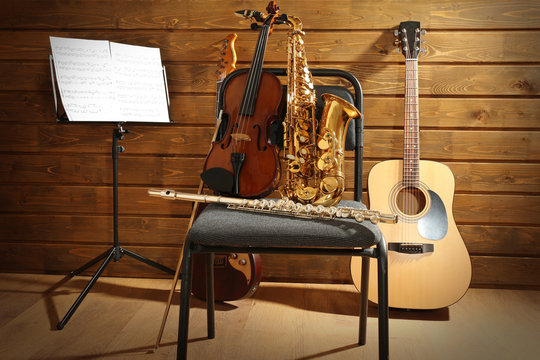 Musical instruments on a chair and note holder against wooden background