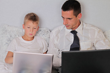 Businessman father with son both using laptop computers. Balance between work and time spent with family