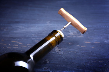 Fototapeta na wymiar Corkscrew and wine bottle on blue wooden background