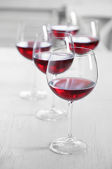 Glasses of red wine on table on bright background