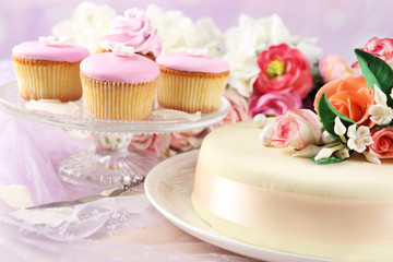 Obraz na płótnie Canvas Cake with sugar paste flowers and cupcakes, on light background