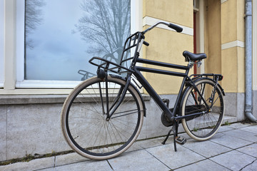 Fototapeta na wymiar Black vintage transport bike parked in front of a house.